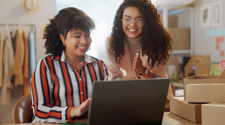 Smiling women working together at desk with laptop
