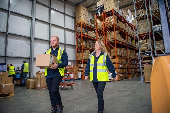 2 people walking through warehouse.