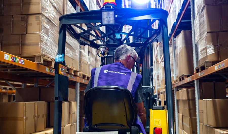 A fulfilmentcrowd worker drives a pallet truck through the warehouse